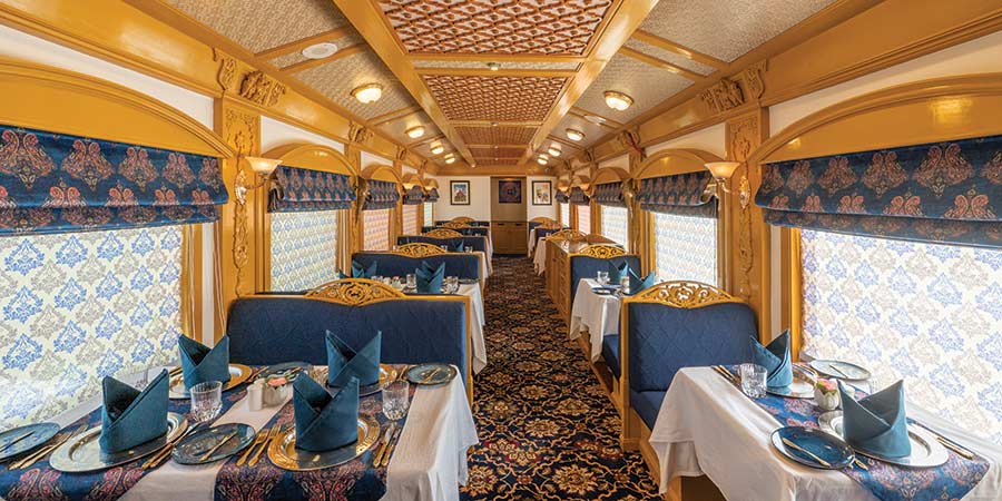 The dining car on the Deccan Odyssey is covered in rich gold and vibrant blue and ornate patterns cover the carpets, curtains and even ceilings. 